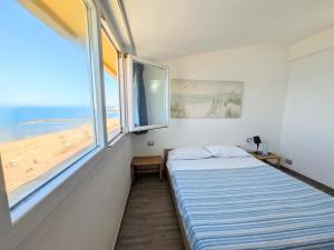 a bedroom with a bed and a window with a beach at ESPRESSO VISTA MARE, Ostia Antica in Lido di Ostia