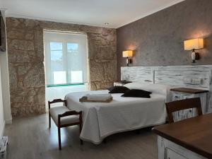 a bedroom with two beds and a table and chairs at Pensión O Prouso in San Mamede de Carnota +45 photos