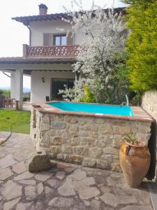 Eine Steinmauer mit einem Swimmingpool vor einem Haus in der Unterkunft Villa Dedo in Reggello