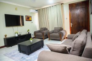 a living room with couches and a flat screen tv at Jeswel Lux villa in Dodoma