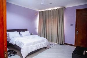 a bedroom with a white bed and purple walls at Jeswel Lux villa in Dodoma