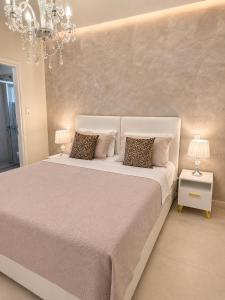 a bedroom with a white bed with pillows and a chandelier at Studios Chrissi-Renovated 2026, Just 20m from the Beach in Skala Sotiros
