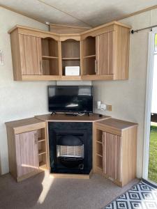 a entertainment center with a fireplace and a television at Holiday home / Caravan in Felpham
