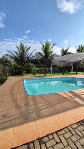 a swimming pool in front of a house with palm trees at Bom sossego in Foz do Iguaçu