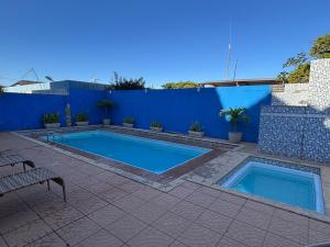 a swimming pool in front of a blue wall at RESTAURANTE POUSADA E ESCUNA RIO SOl in São João da Barra
