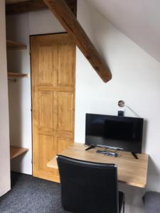 a room with a desk with a television and a wooden door at Privát u koní in Úherce