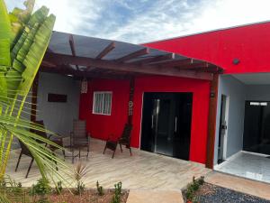 a house with a red wall and chairs on a deck at PousadaOasis in Várzea Grande