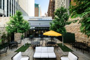 a patio with tables and chairs and a yellow umbrella at Surety Hotel, Autograph Collection in Des Moines