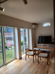 a living room with a table and chairs and a television at Guesthouse Oomiyabase25 大宮基地 別荘新館 in Chiba