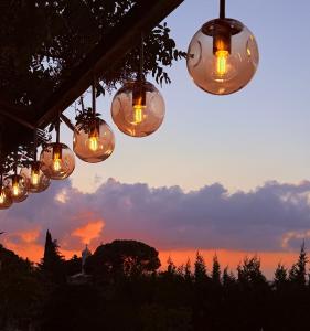 a group of lights hanging from a roof with a sunset at Boreas Retreat - Mountain Escape & Spa in Batroûn +33 photos