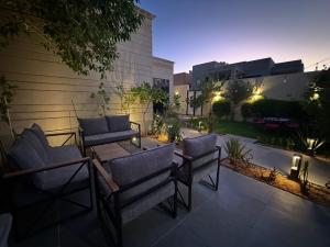 a patio with chairs and a table and a building at Grey Villa in Buraydah