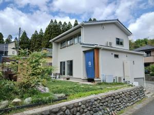 a white house with a blue door at Guesthouse Oomiyabase25 大宮基地 別荘新館 in Chiba