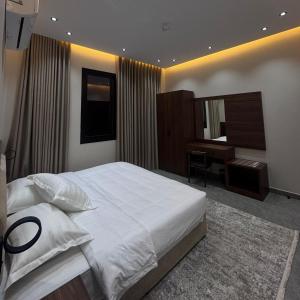 a bedroom with a large white bed and a desk at Misk Apartment in Jeddah