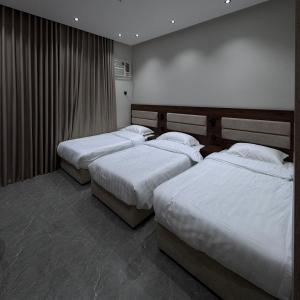 a bedroom with two beds with white sheets at Misk Apartment in Jeddah +12 photos