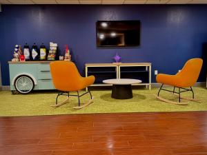 a room with two chairs and a table and a tv at Spark by Hilton Waynesboro in Waynesboro