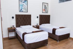 two beds in a hotel room with white walls at Zentra Plaza Hotel & Cowork in Chiclayo