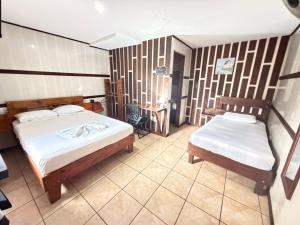 a bedroom with two beds and a chair in it at Hotel Don Roberto in San Isidro de El General +22 photos