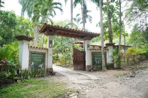 a gate to a house in a forest with palm trees at EcoHotel Inka Minka in Santa Marta