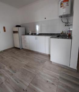 a kitchen with white cabinets and a wooden floor at Casona Villa Helena in Miramar +10 photos