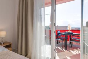 a bedroom with a bed and a balcony with a table at Apartments Mare in Punat