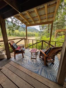 a porch of a cabin with two chairs and a table at Magnolia Cottage Bigfoot Hideaway in Hope