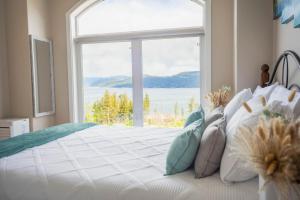 a bedroom with a bed with a large window at Panoramic Acres B & B - Lake & Mountain Views in Vernon +11 photos