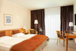ein Hotelzimmer mit einem großen Bett und einem Schreibtisch in der Unterkunft Wyndham Hannover Atrium in Hannover