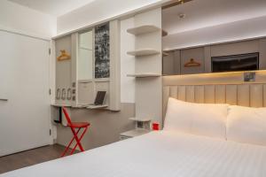 a bedroom with a white bed and a red chair at Point A Hotel Glasgow in Glasgow