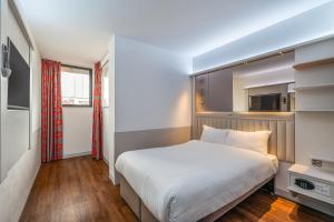 a bedroom with a white bed and a kitchen at Point A Hotel Glasgow in Glasgow