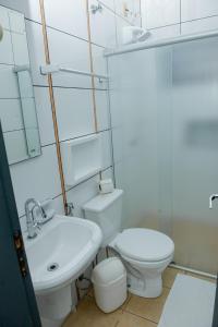 a white bathroom with a toilet and a sink at Hotel Universitario in Itapetininga +42 photos