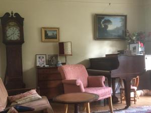 a living room with a piano and a chair at private room in Leamington Spa
