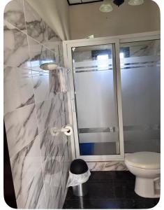 a bathroom with a toilet and a glass shower at Ondinas Weekend Spot in La Ceiba
