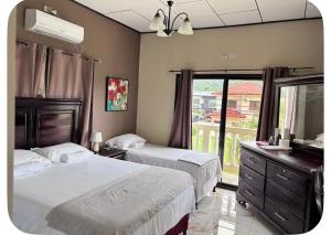 a bedroom with two beds and a television and a window at Ondinas Weekend Spot in La Ceiba
