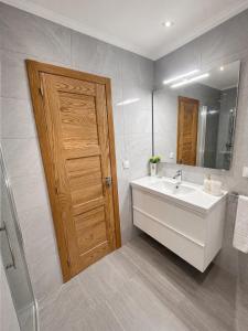 a bathroom with a white sink and a wooden door at Casa da Xastra in Vimianzo +11 photos