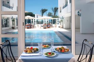 a table with two plates of food next to a pool at Swiss Wellness Boutique Hotel Hurghada in Hurghada