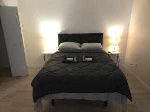 a bed with a black comforter and two side tables at unique Two -Bedroom Central Townhouse in Vancouver +2 photos