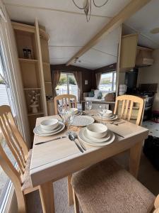 a table with plates and glasses on it in a kitchen at Welsh Bay Hideaway 2 bed caravan with sun deck in Aberystwyth +21 photos