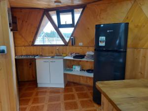 a kitchen with a black refrigerator in a cabin at Domos Maran Lican Ray in Licán Ray