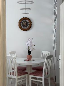 a white table with chairs and a clock on the wall at Apartman VIA in Žabljak +21 photos