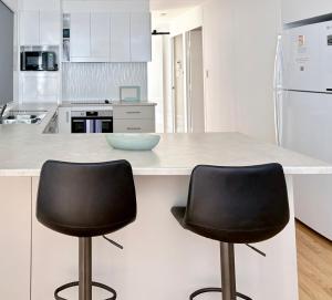 a kitchen with two black chairs at a counter at Rainbow House in Rainbow Beach +12 photos
