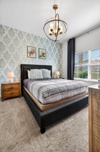 a bedroom with a large bed and a chandelier at 1556 PD - Poolside Bliss: Enchanted 4BR Townhome in Davenport