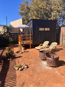 a yard with two chairs and a black trailer at La Ola Tiny House in Maitencillo