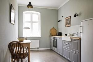 a kitchen with gray cabinets and a table and a window at Leuchtturnwohnung in Pommerby