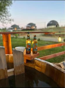 two bottles of beer sitting on top of a fence at Tiny House in Trape