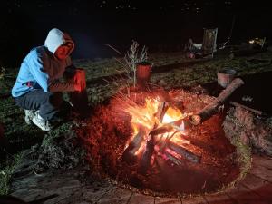 a person is sitting next to a fire at Zona de camping zoe in Guatavita