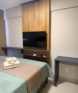 a room with a bed and a television on a wall at Apartamento - Leblon 409 Conforto & Estilo. in Cuiabá