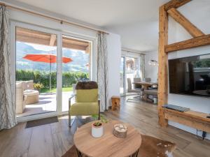 a living room with a television and a table and a chair at Sonnen Lodge Kaprun in Piesendorf