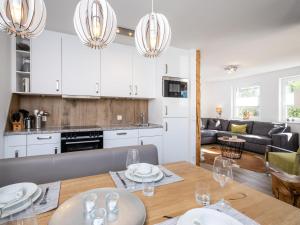 a kitchen and living room with white cabinets and a table at Sonnen Lodge Kaprun in Piesendorf
