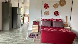 a bedroom with a red bed and a kitchen at KOKI Horizon in Atuona