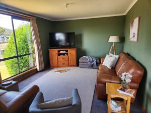 ein Wohnzimmer mit Sofa und Fernseher in der Unterkunft Zeehan Affect in Zeehan